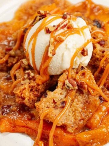 Crock Pot Peach Cobbler with Cake Mix is an easy slow cooker dessert recipe using canned peach slices, boxed butter pecan cake mix, brown sugar, cinnamon, butter and chopped pecans.