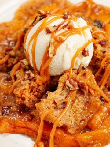 Crock Pot Peach Cobbler with Cake Mix is an easy slow cooker dessert recipe using canned peach slices, boxed butter pecan cake mix, brown sugar, cinnamon, butter and chopped pecans.