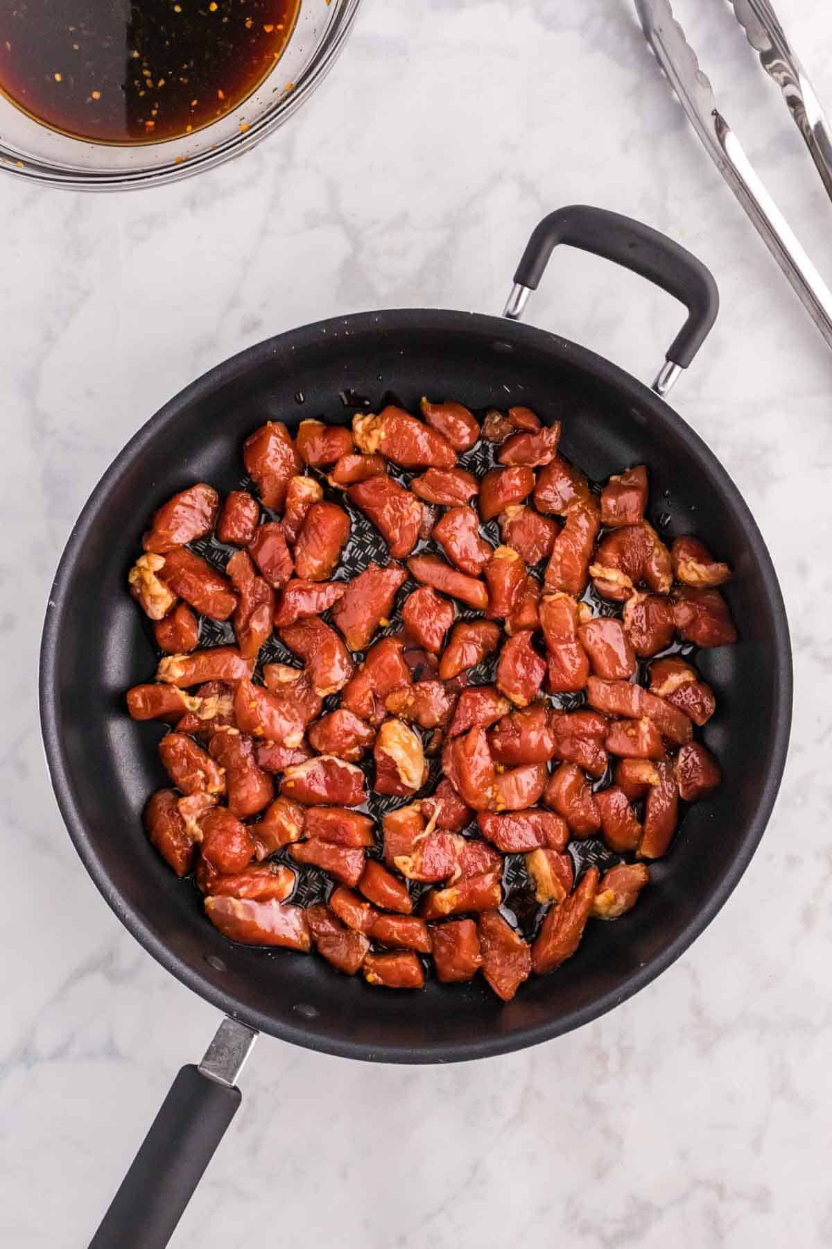 pork pieces added to a hot skillet