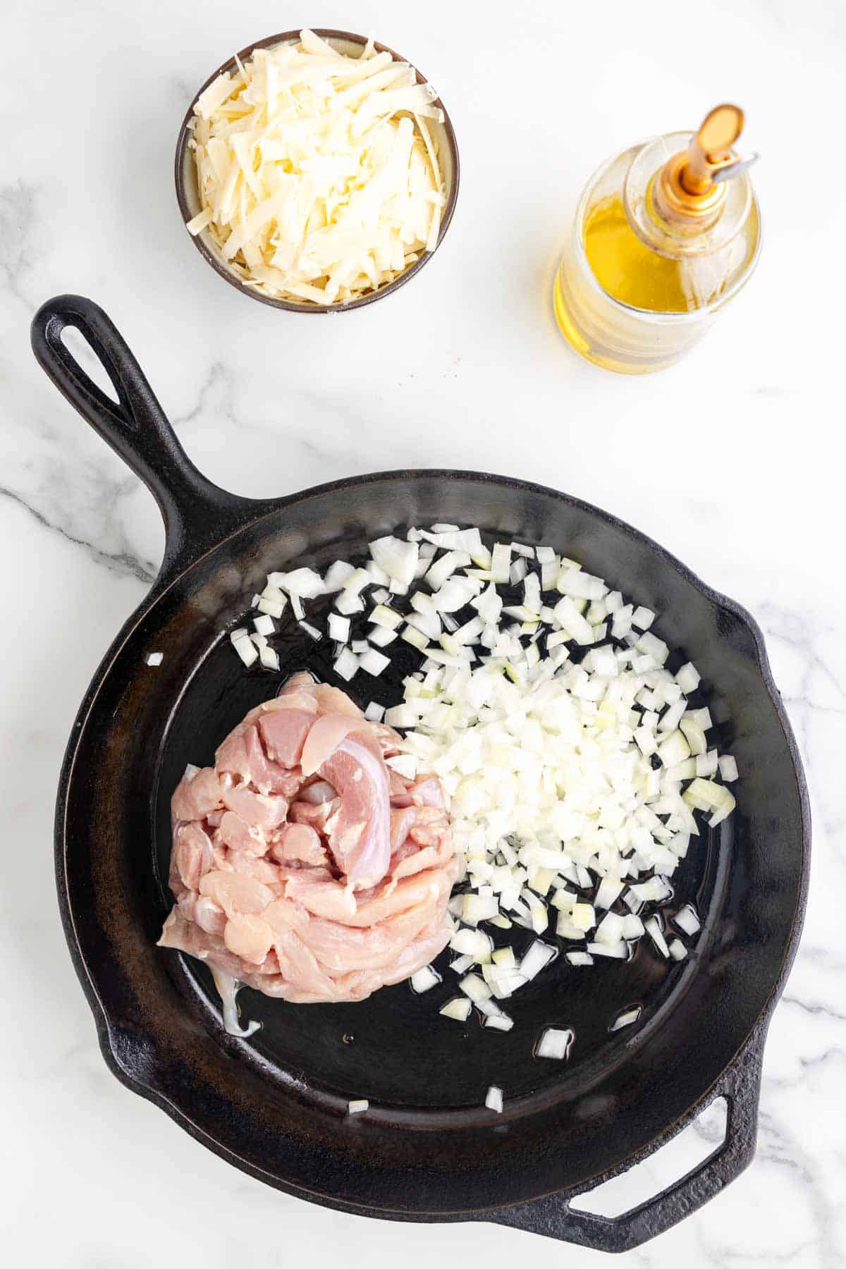 raw chicken strips and diced onions in a skillet