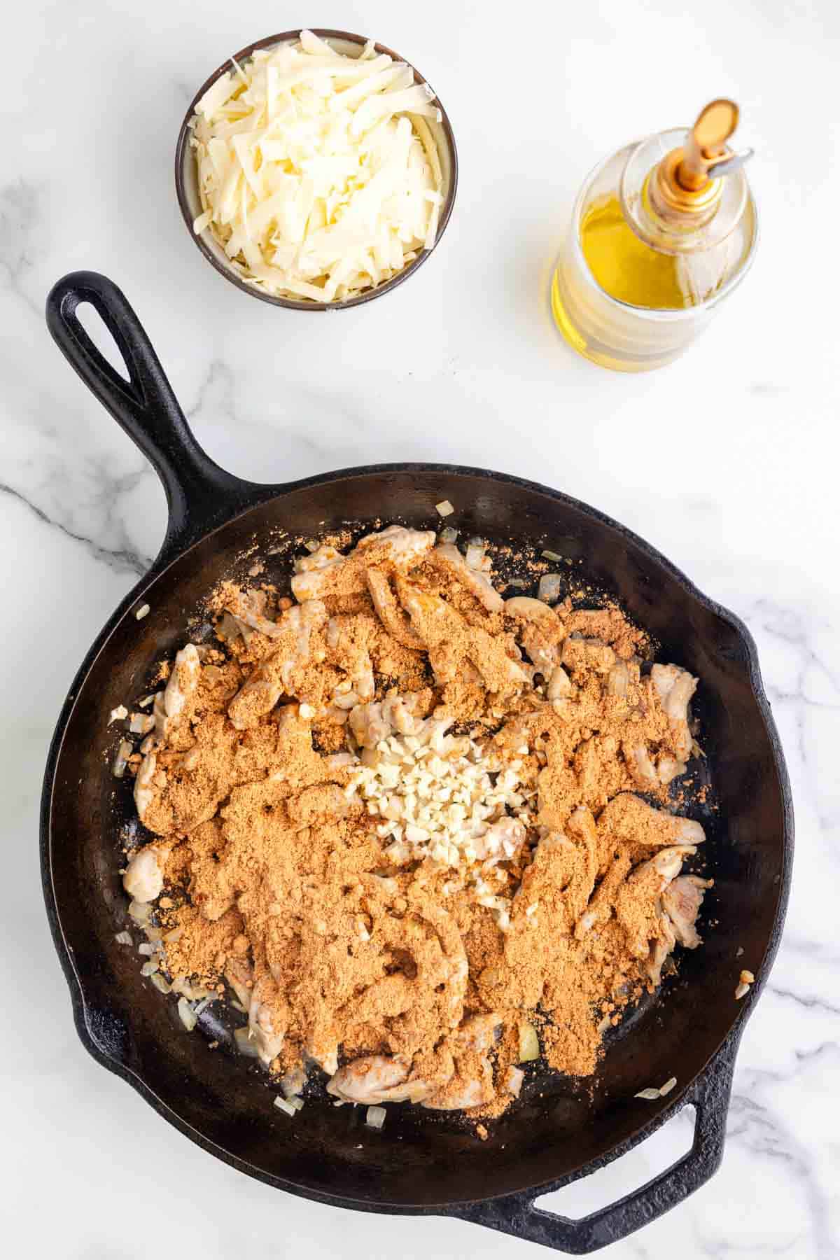 minced garlic and taco seasoning on top of cooked chicken strips in a skillet