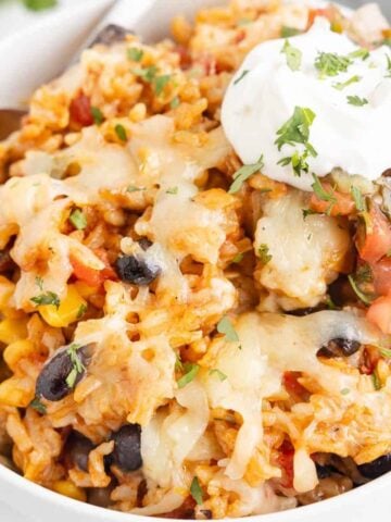 One Pan Cheesy Taco Chicken and Rice is an easy stove top dinner recipe loaded with chicken thigh chunks, Rotel, corn, black beans, taco seasoning, rice and shredded cheese.