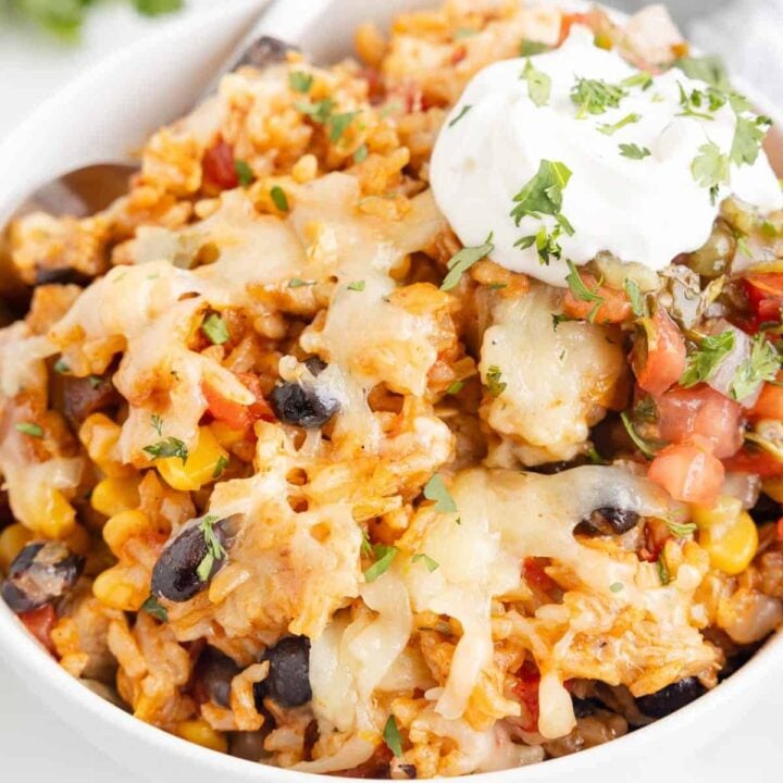 One Pan Cheesy Taco Chicken and Rice is an easy stove top dinner recipe loaded with chicken thigh chunks, Rotel, corn, black beans, taco seasoning, rice and shredded cheese.