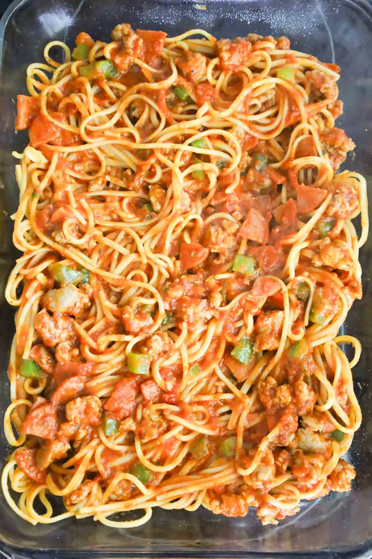 spaghetti with pepperoni and diced peppers in a baking dish