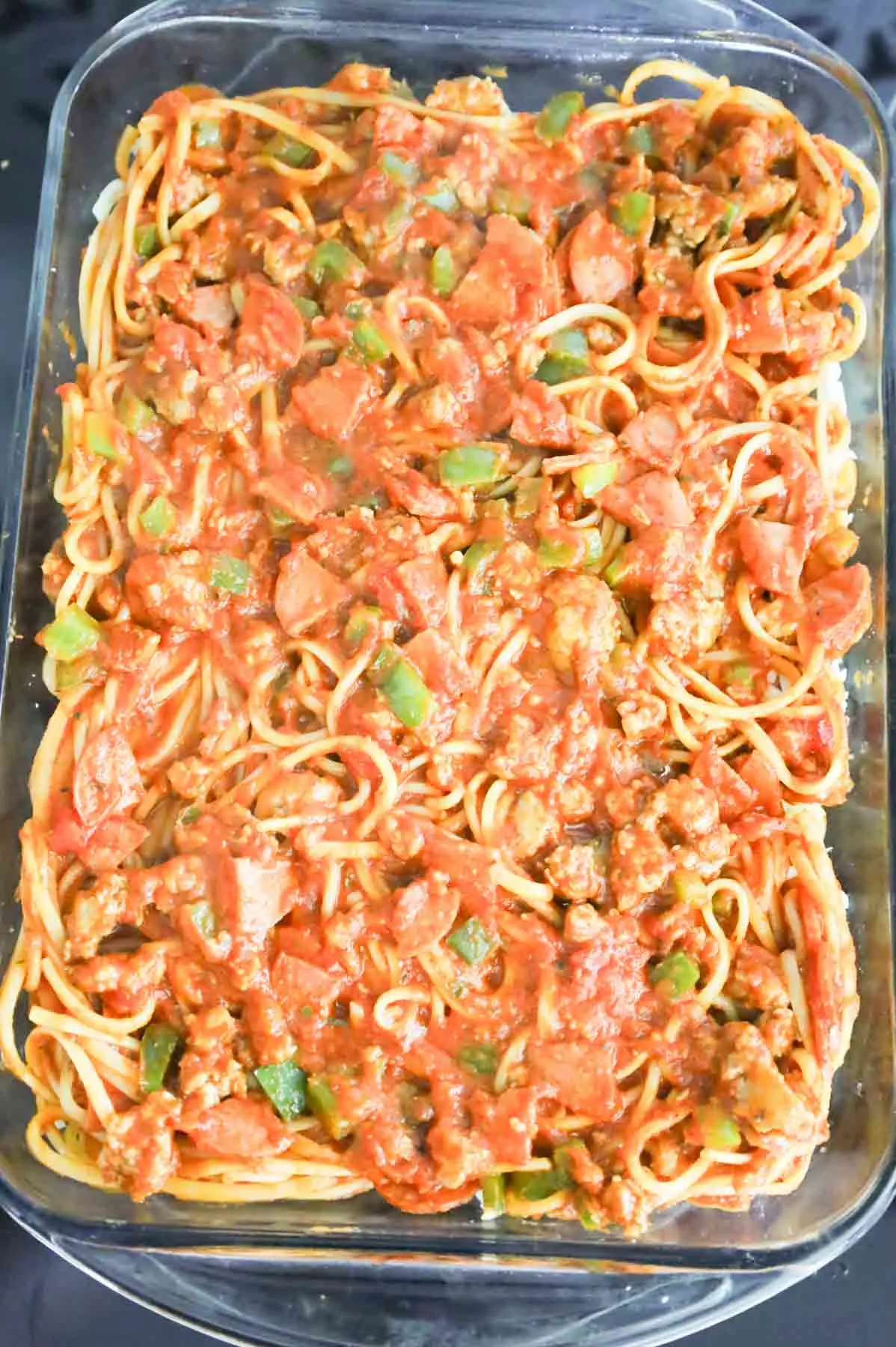 pepperoni, diced peppers and sausage spaghetti mixture in a baking dish