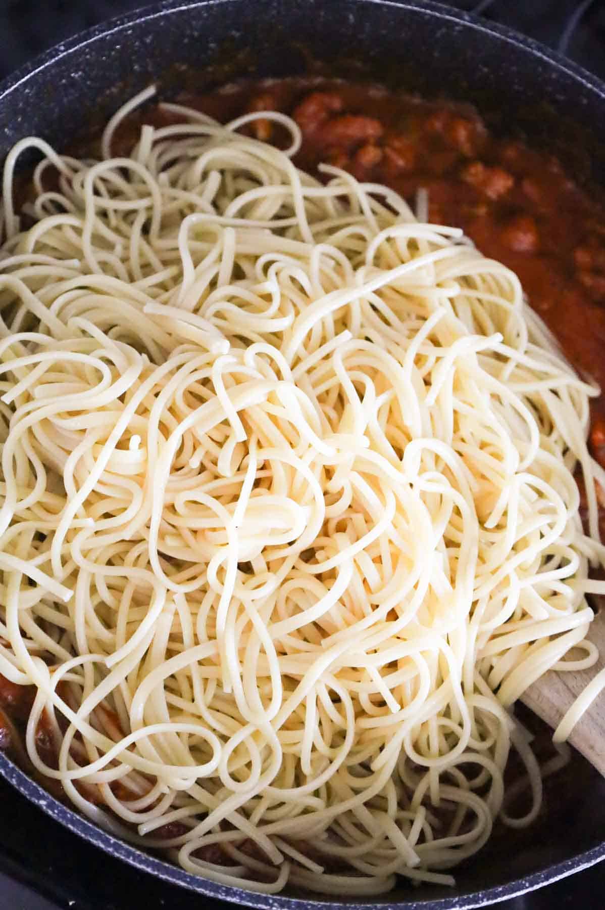 cooked spaghetti noodles added to skillet with sauce and meat mixture
