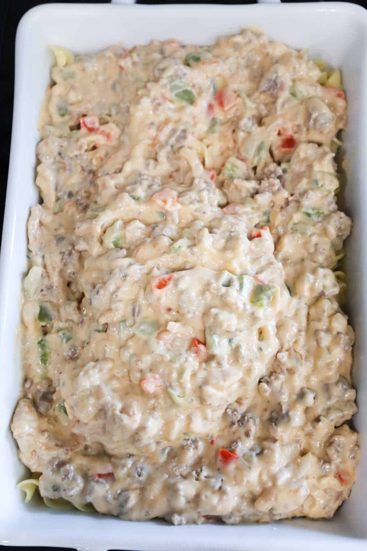 creamy sausage mixture poured over cooked noodles in a baking dish