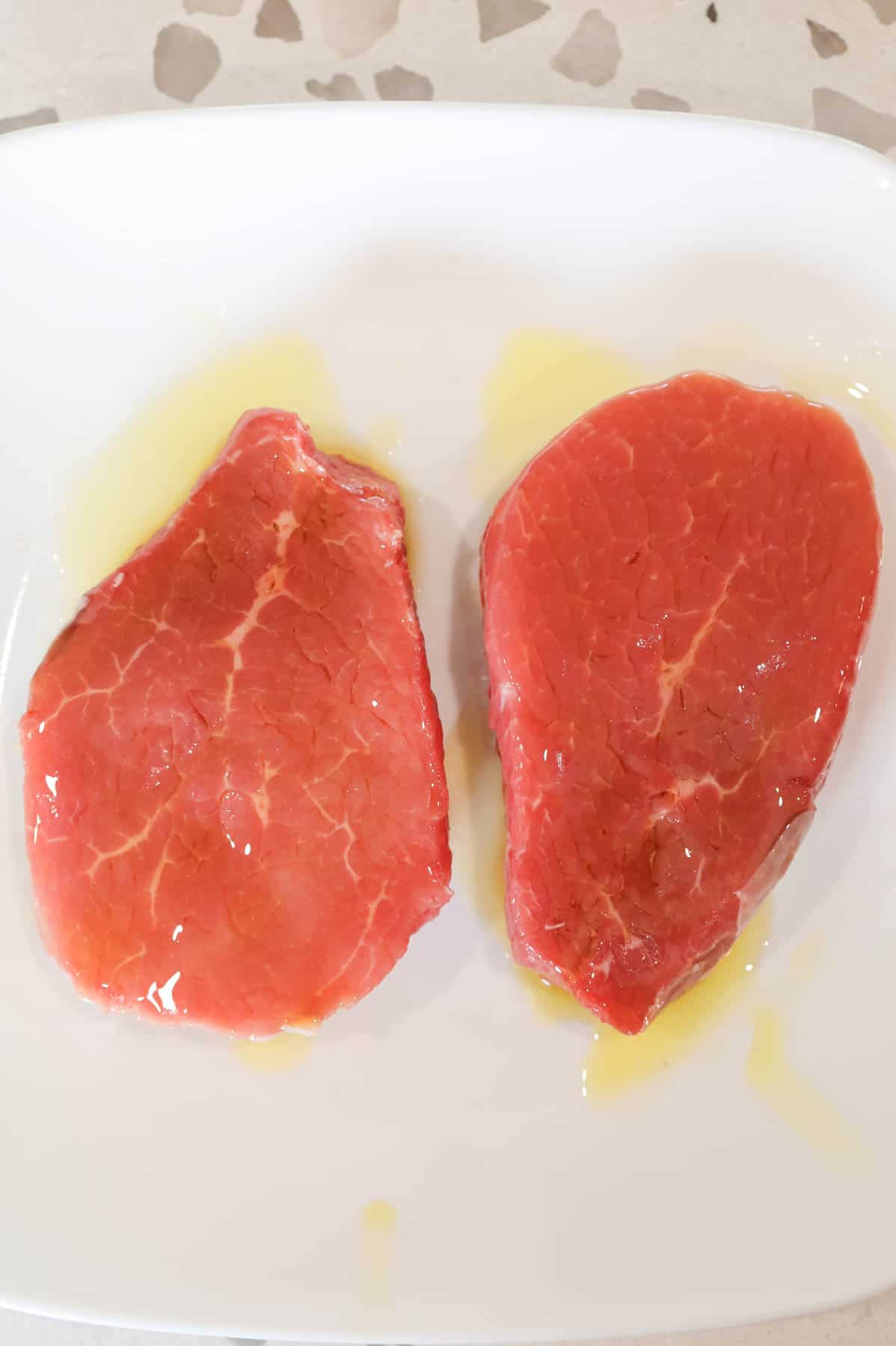 steaks coated in olive oil on a plate