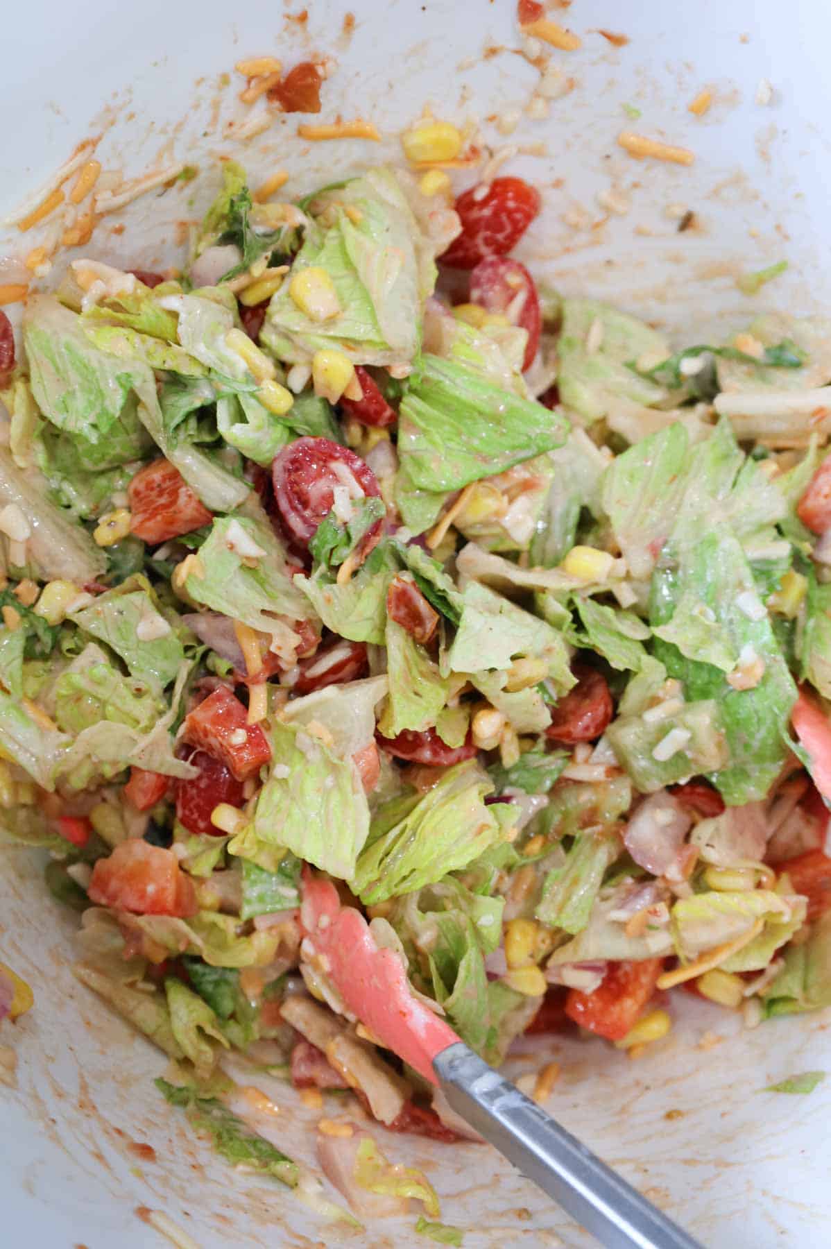 taco salad tossed with dressing in a bowl