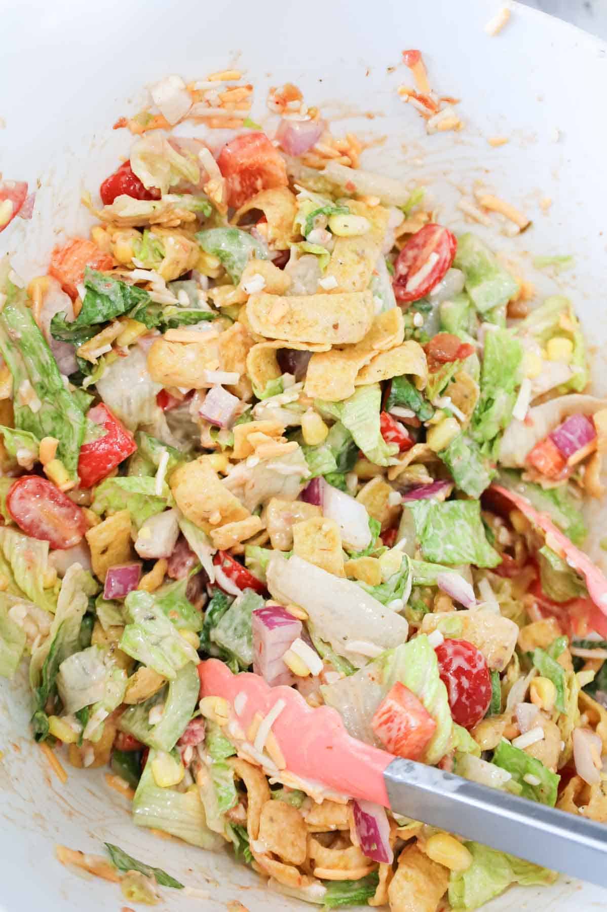 taco salad and dressing being tossed in a skillet
