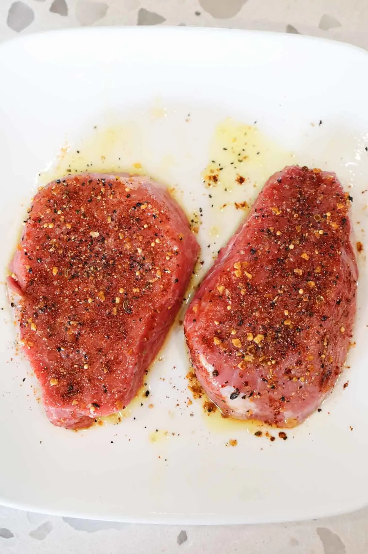 seasoned and oiled steaks on a plate