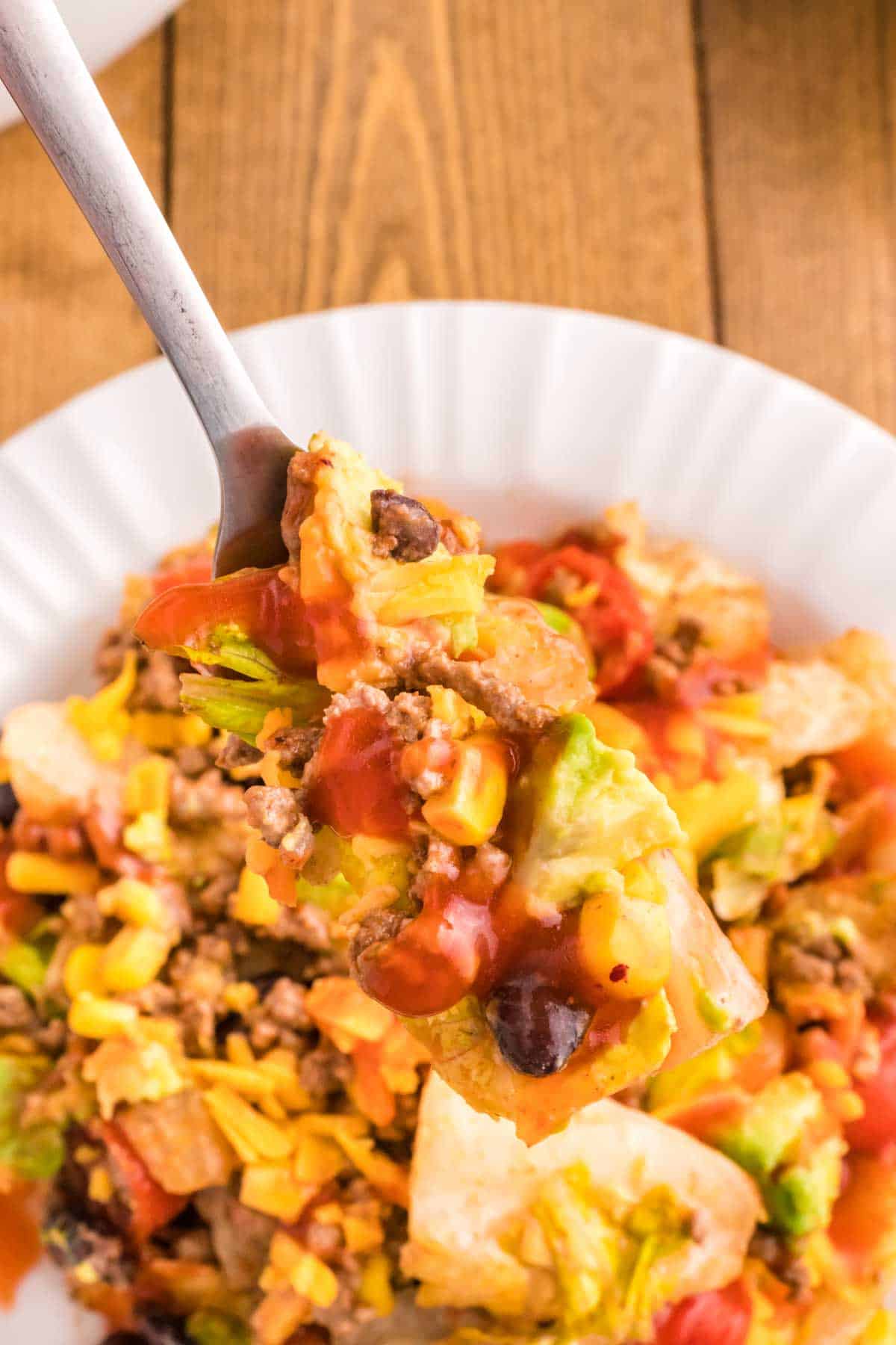 Taco Salad with Catalina Dressing is a hearty salad recipe loaded with taco seasoned ground beef, romaine lettuce, cherry tomatoes, cheddar cheese, crushed tortilla chips, corn, black bean and diced avocados all tossed in a sour cream and Catalina based dressing.