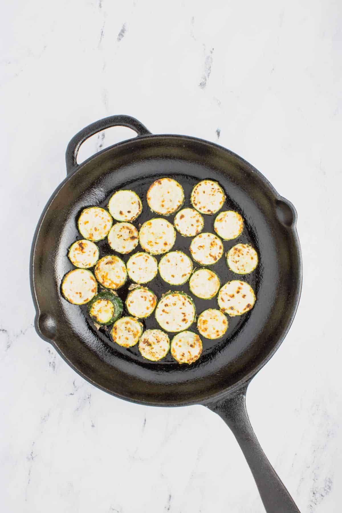 zucchini slices cooking in a skillet