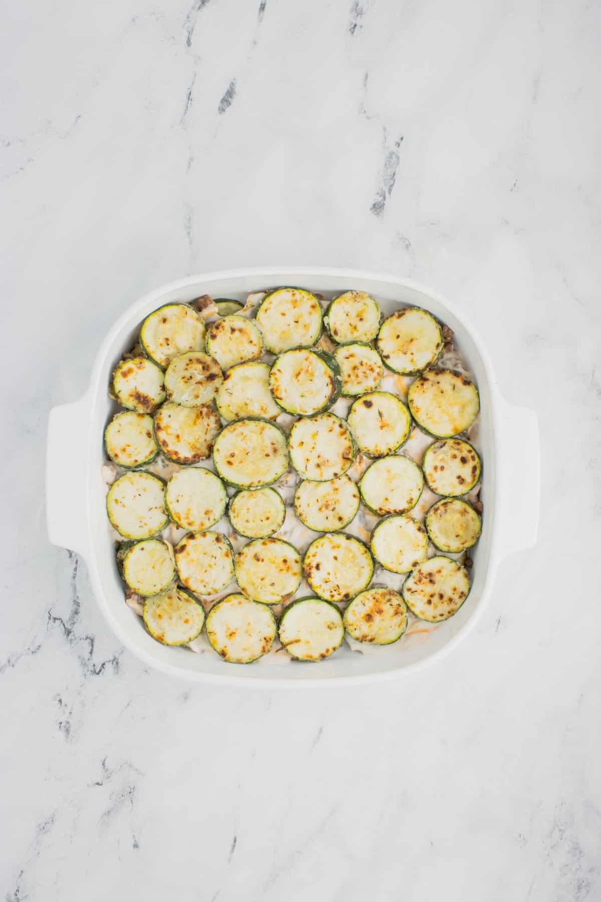 sauteed zucchini slices on top of creamy soup mixture in a baking dish