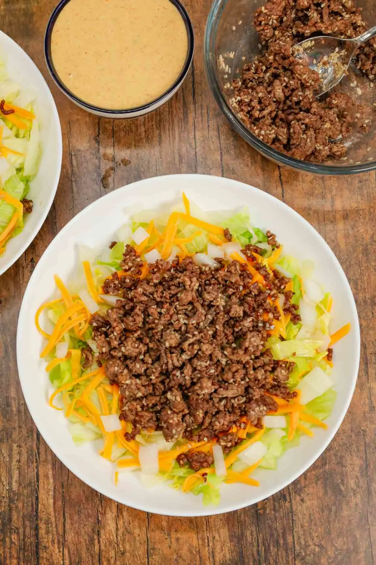 cooked ground beef on top of shredded cheddar and lettuce on a plate