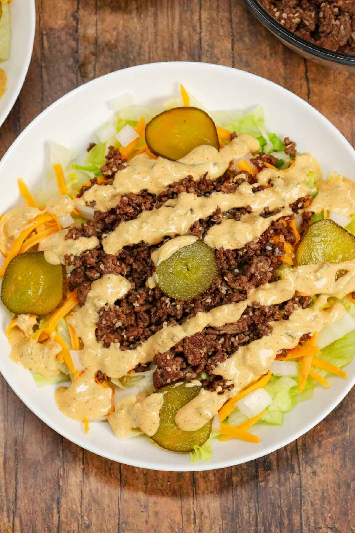 Big Mac Salad is a hearty dinner recipe loaded with ground beef, shredded cheddar cheese, iceberg lettuce, diced onions, dill pickles, sesame seeds and a homemade Big Mac sauce.