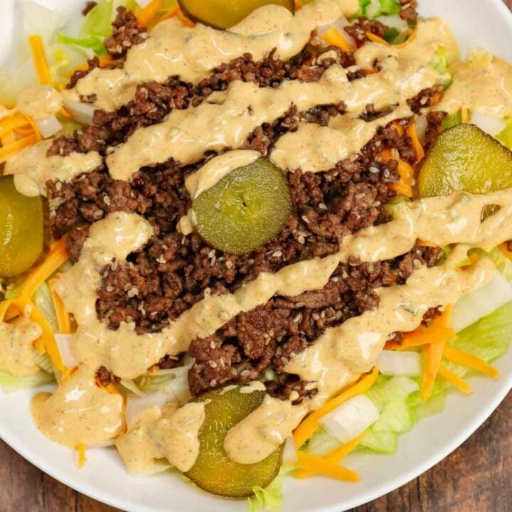 Big Mac Salad is a hearty dinner recipe loaded with ground beef, shredded cheddar cheese, iceberg lettuce, diced onions, dill pickles, sesame seeds and a homemade Big Mac sauce.