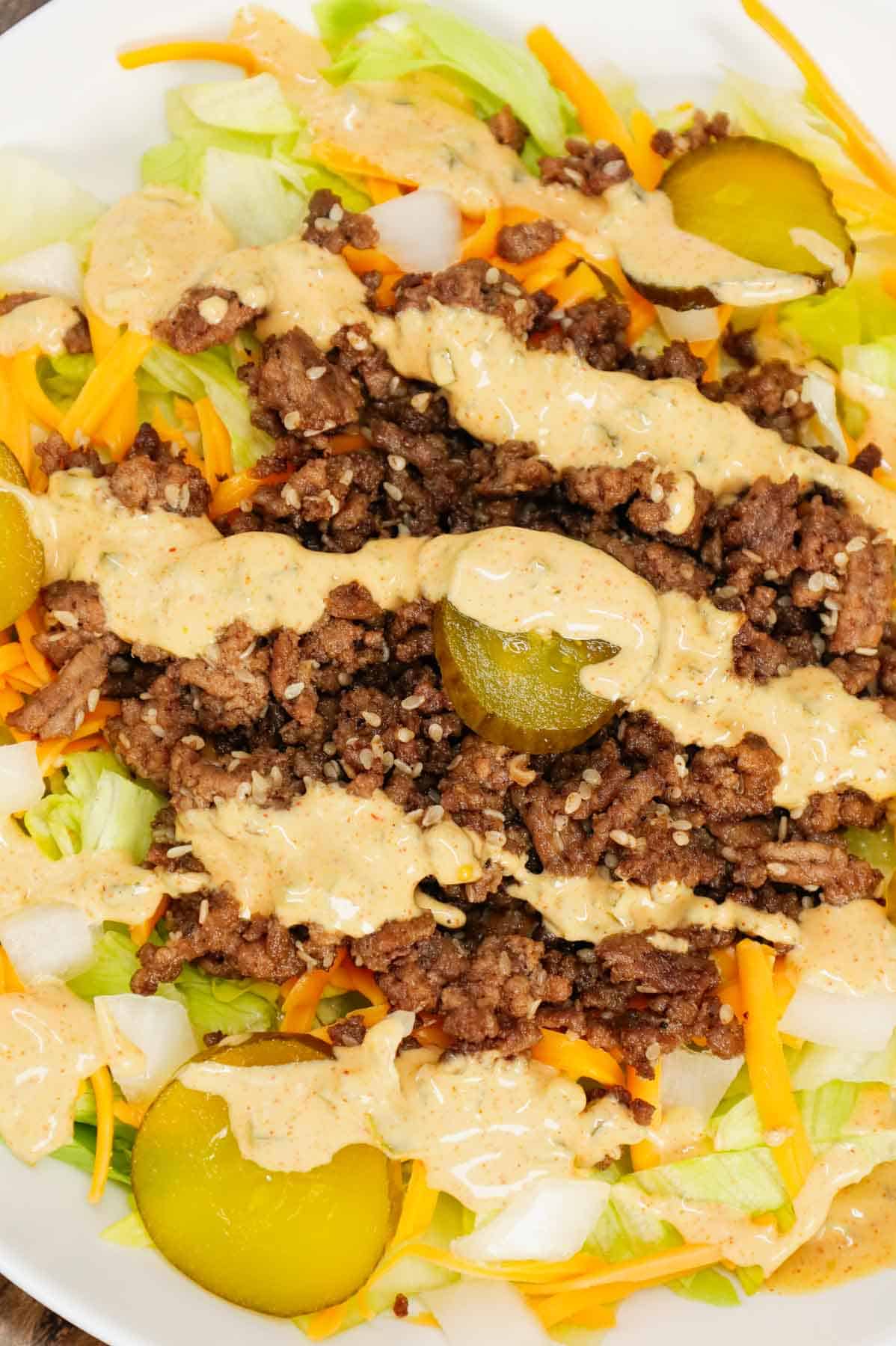 Big Mac Salad is a hearty dinner recipe loaded with ground beef, shredded cheddar cheese, iceberg lettuce, diced onions, dill pickles, sesame seeds and a homemade Big Mac sauce.