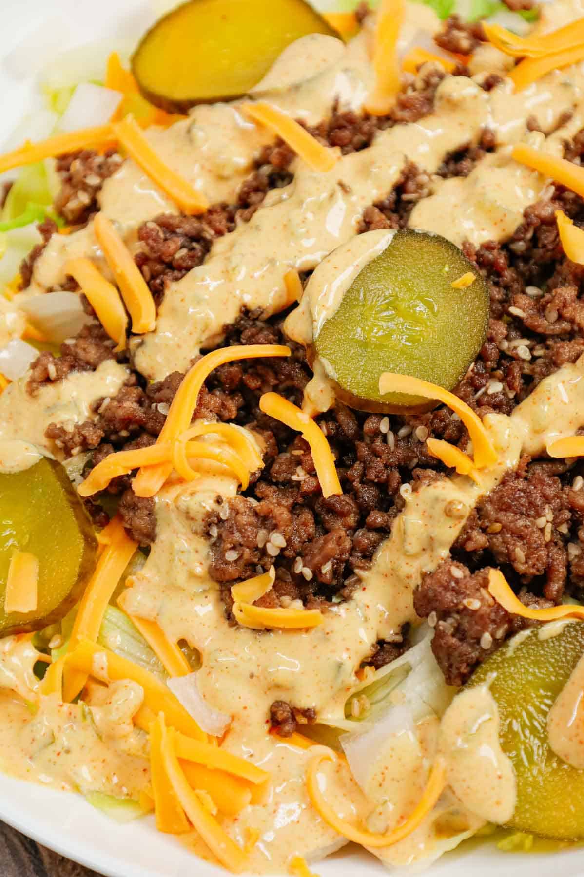 Big Mac Salad is a hearty dinner recipe loaded with ground beef, shredded cheddar cheese, iceberg lettuce, diced onions, dill pickles, sesame seeds and a homemade Big Mac sauce.