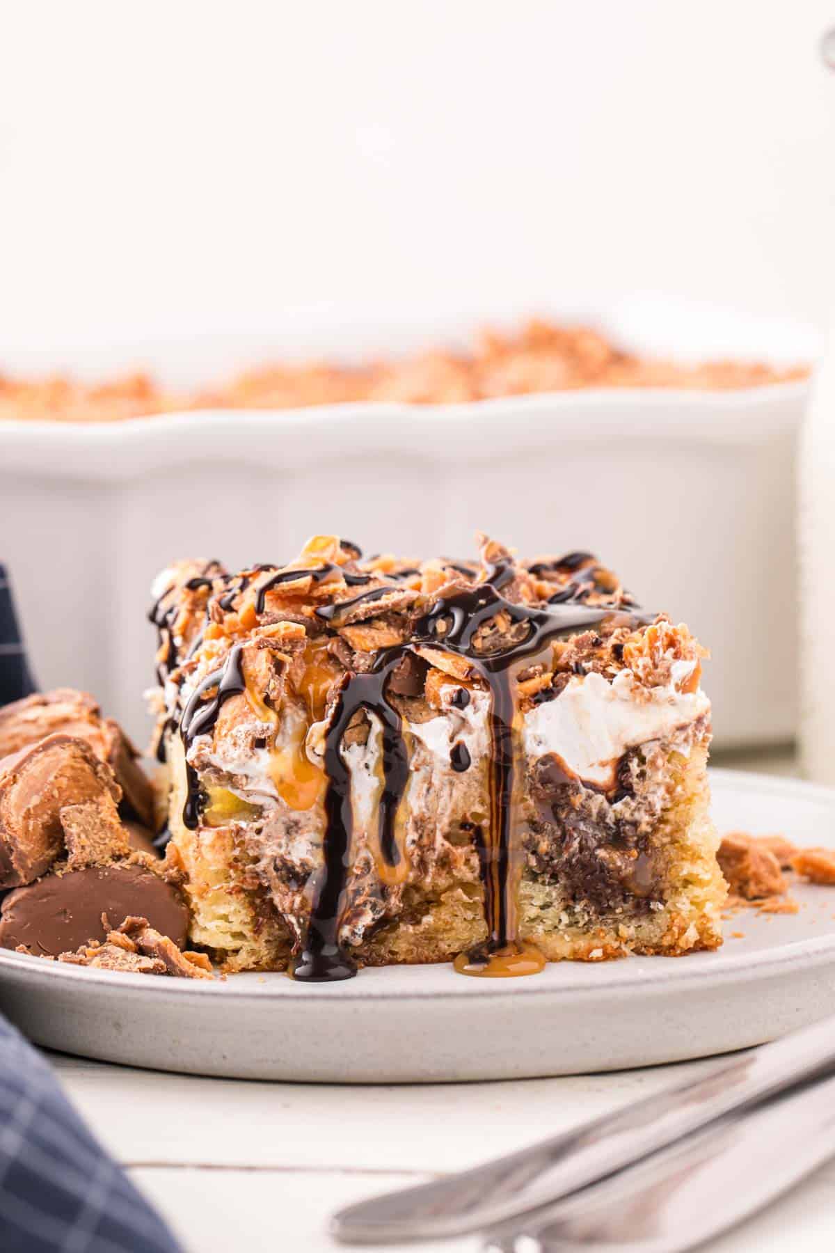 Butterfinger Poke Cake is a decadent dessert starting with a golden cake filled with chocolate and caramel sauce and topped with whipped topping and chopped Butterfinger chocolate bars.
