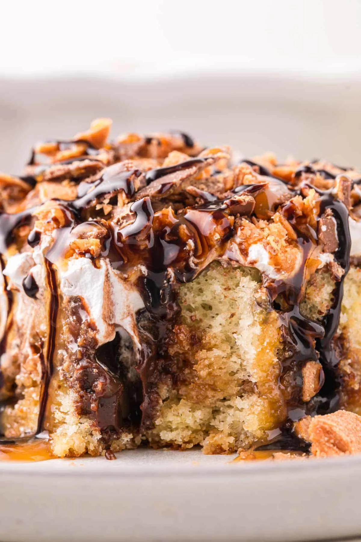 Butterfinger Poke Cake is a decadent dessert starting with a golden cake filled with chocolate and caramel sauce and topped with whipped topping and chopped Butterfinger chocolate bars.