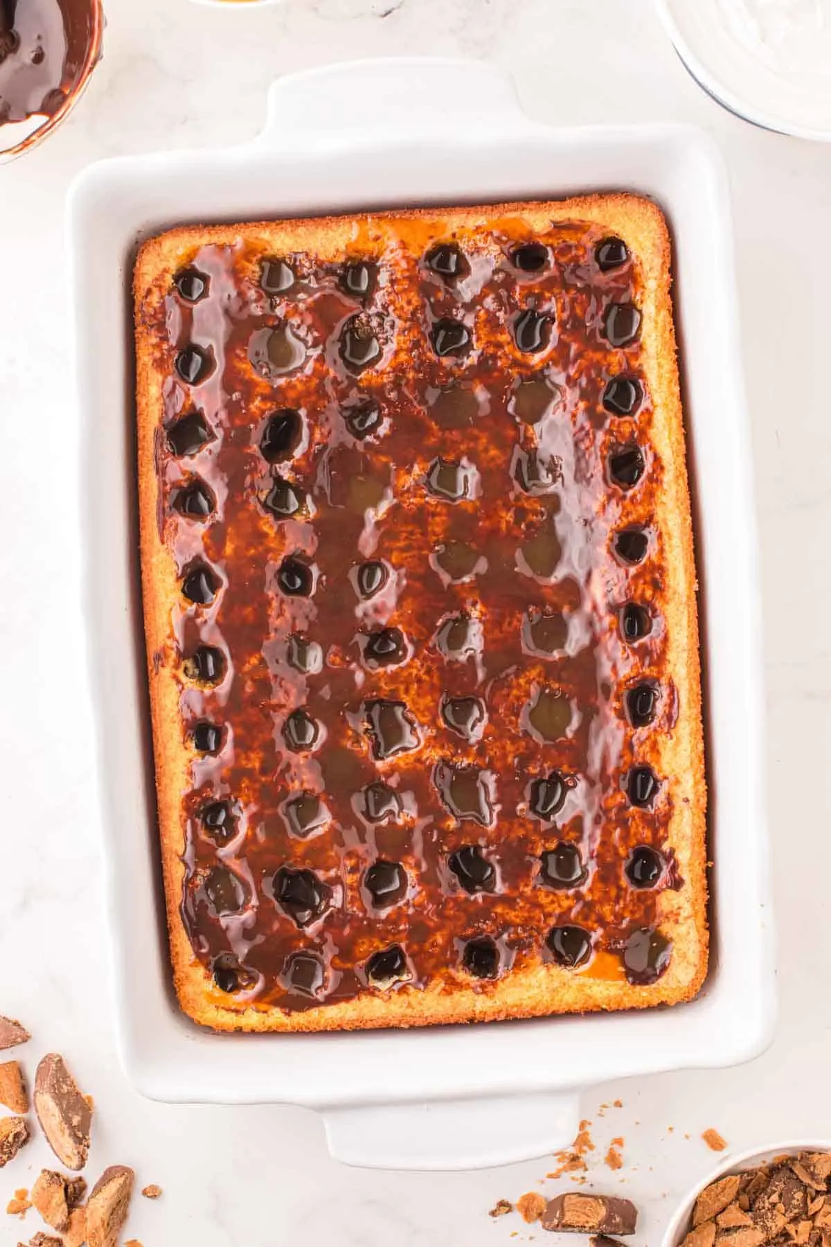caramel and chocolate sauce poured over cake with rows of holes in it