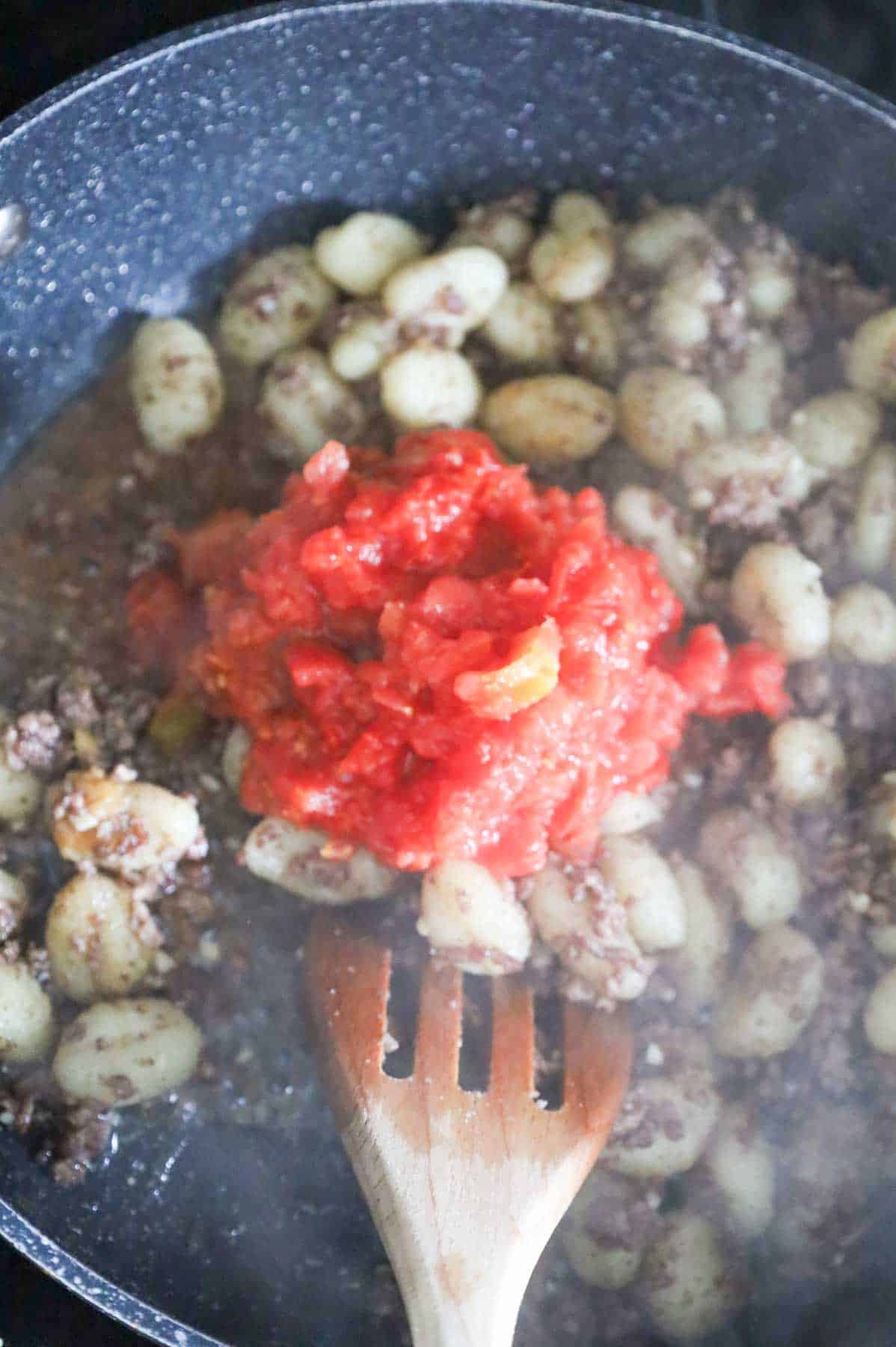 Rotel on top of gnocchi and ground beef mixture in a skillet