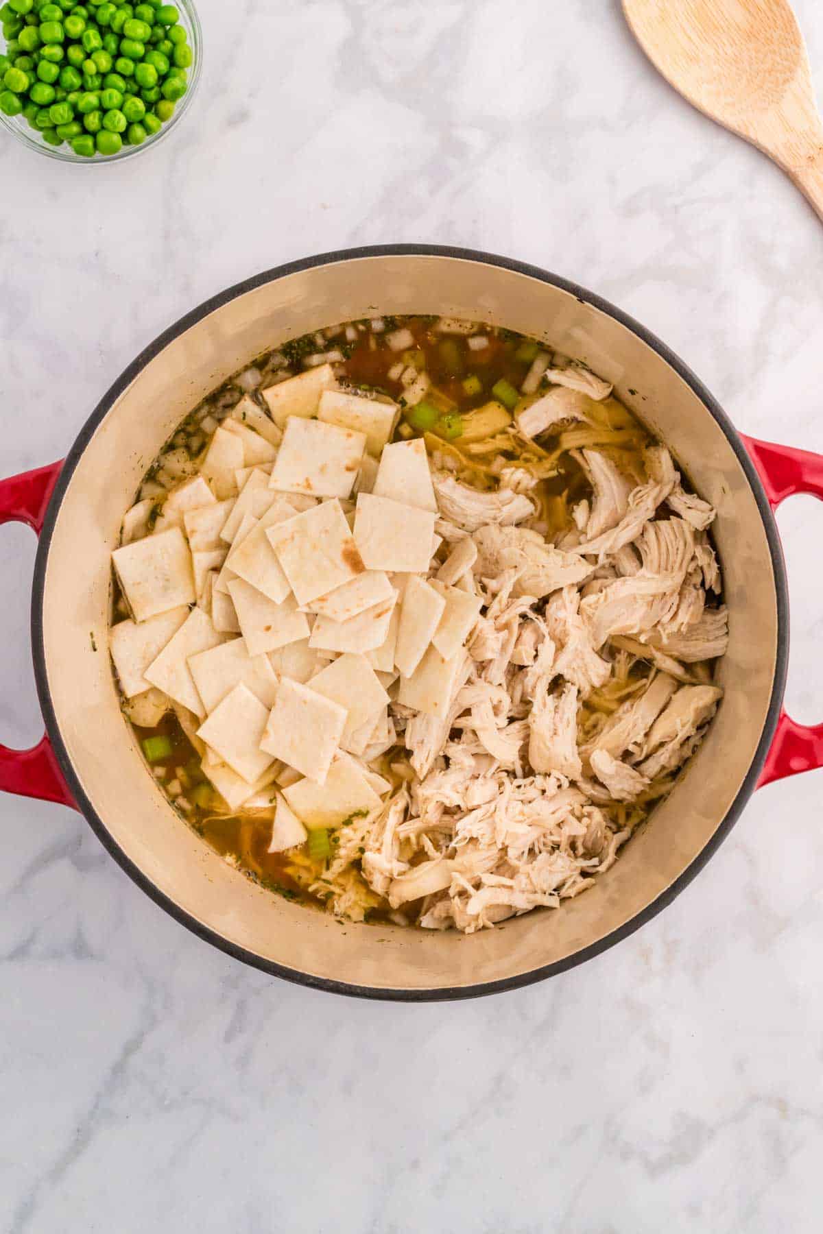 flour tortilla squares and shredded chicken added to pot with veggies and broth