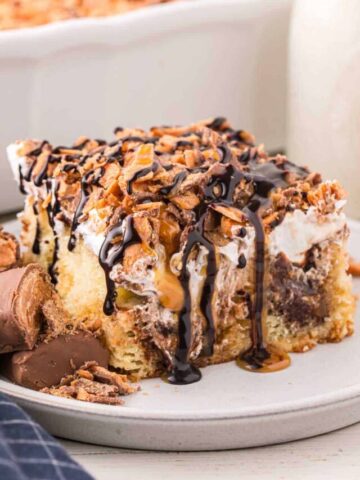 Butterfinger Poke Cake is a decadent dessert starting with a golden cake filled with chocolate and caramel sauce and topped with whipped topping and chopped Butterfinger chocolate bars.