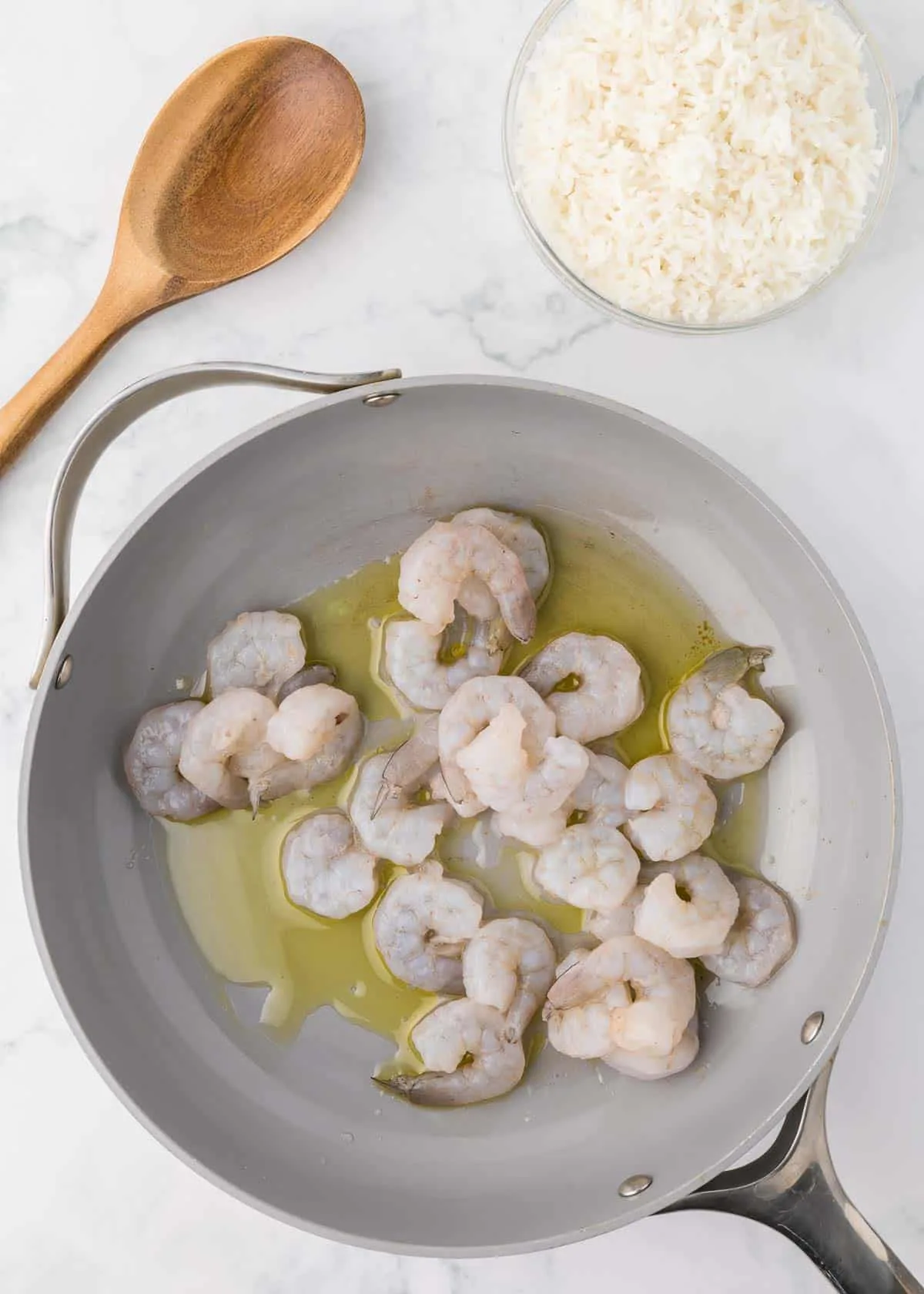 raw shrimp in a skillet with olive oil
