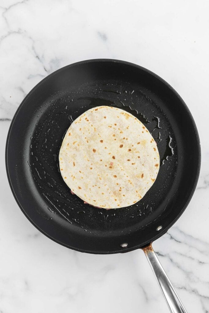 smash burger taco in a skillet, tortilla side up