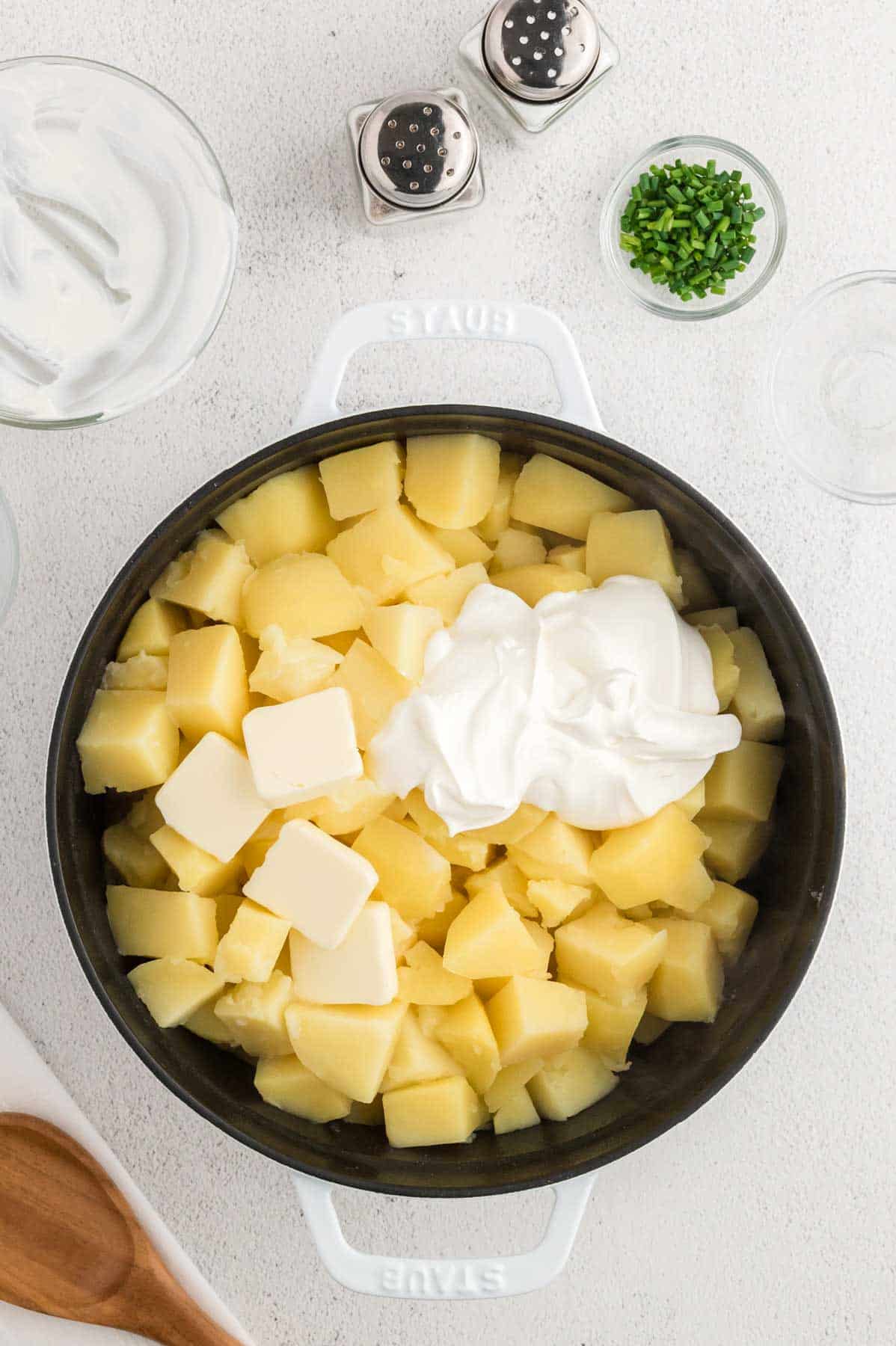 sour cream and butter on top of cooked potato cubes in a pot