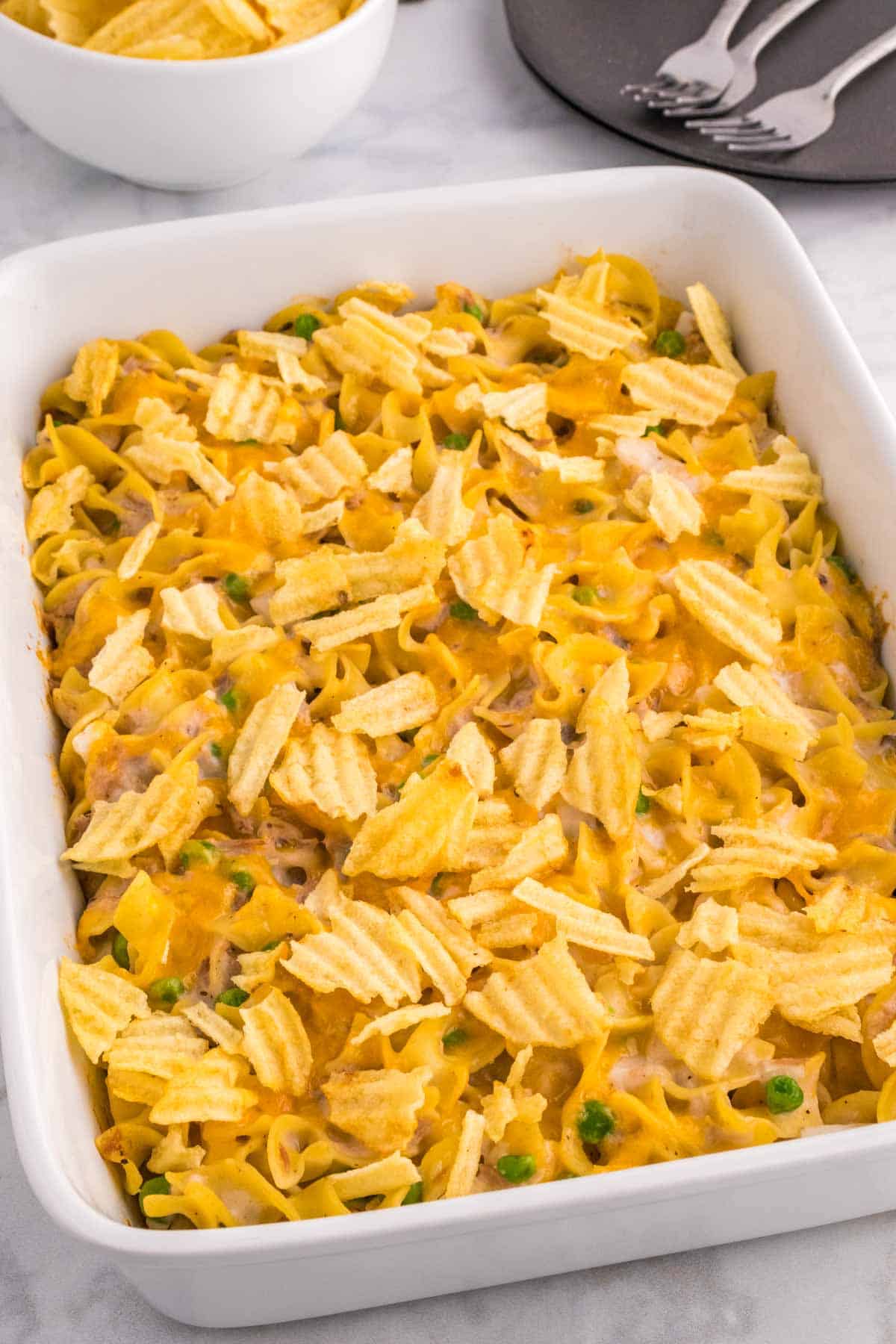 Tuna Casserole with Potato Chips is an easy dinner recipe loaded with egg noodles, canned tuna, peas, diced onions, cream of mushroom soup and shredded cheddar cheese with a crushed potato chip topping.