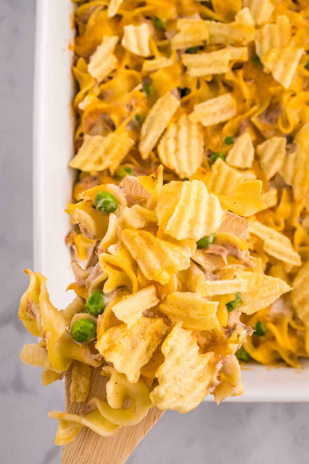 Tuna Casserole with Potato Chips is an easy dinner recipe loaded with egg noodles, canned tuna, peas, diced onions, cream of mushroom soup and shredded cheddar cheese with a crushed potato chip topping.