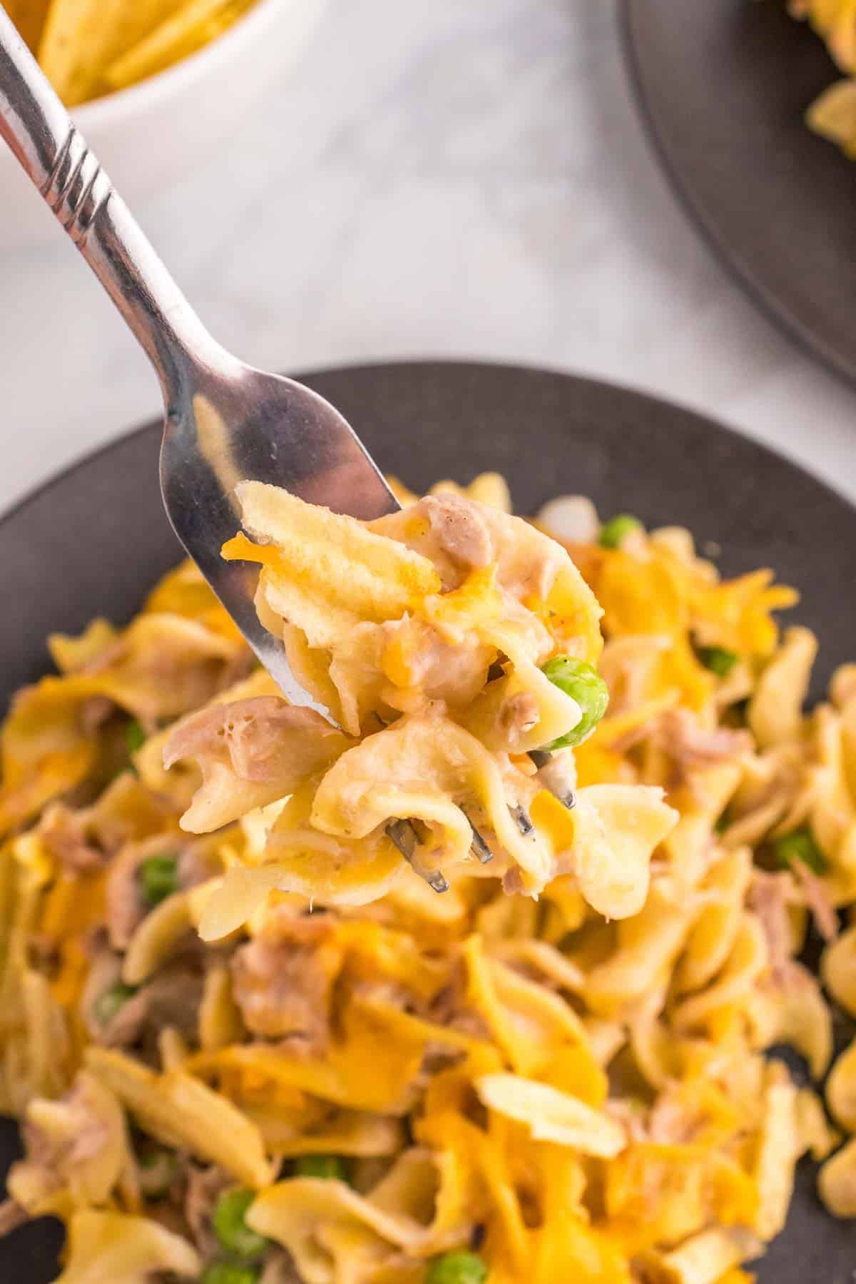 Tuna Casserole with Potato Chips is an easy dinner recipe loaded with egg noodles, canned tuna, peas, diced onions, cream of mushroom soup and shredded cheddar cheese with a crushed potato chip topping.