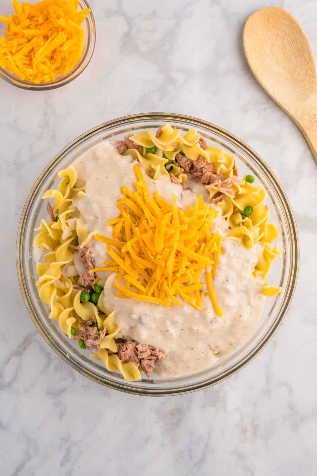 shredded cheddar cheese on top of soup mixture and noodles in a bowl