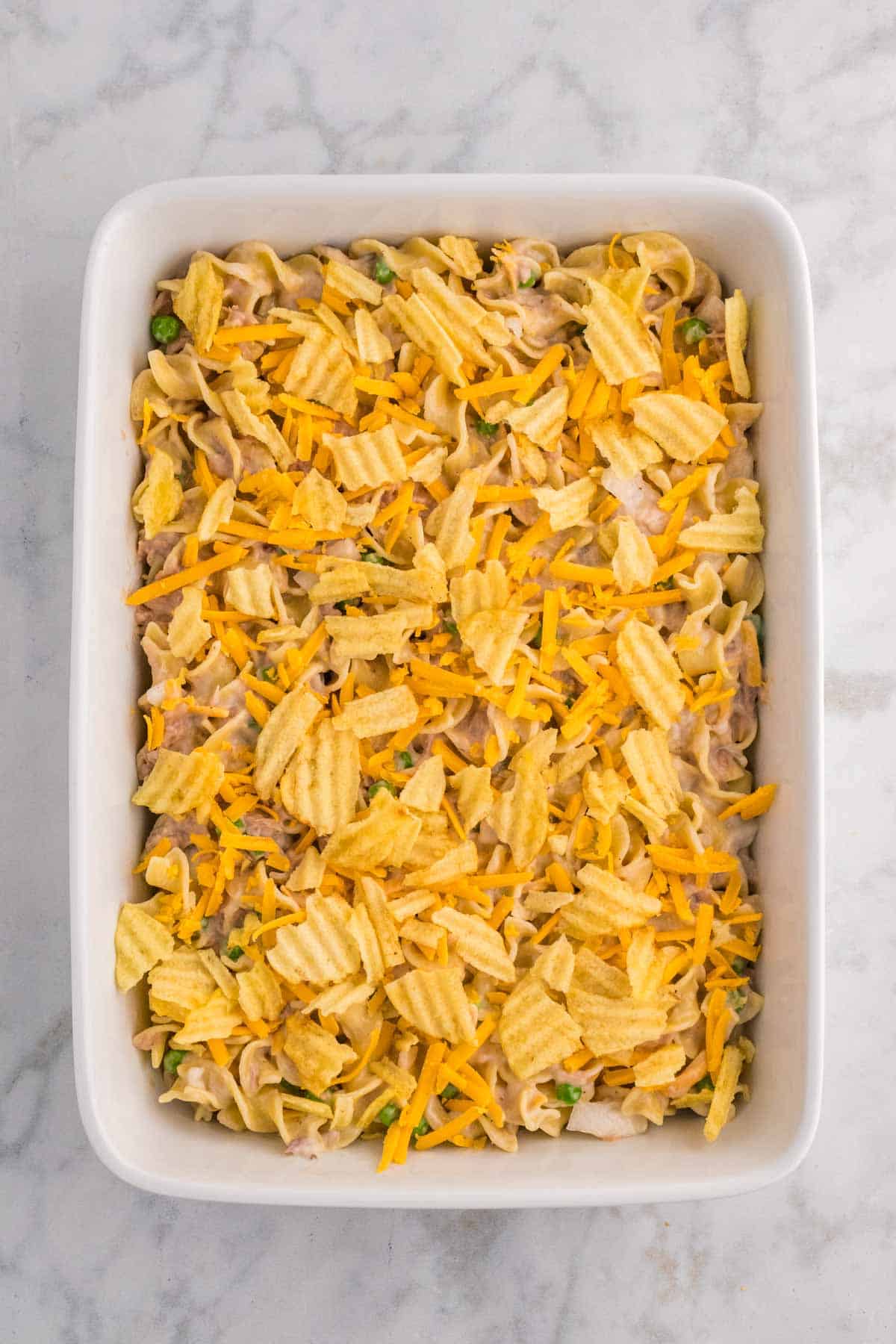 crushed potato chips and shredded cheddar cheese on top of tuna noodle casserole