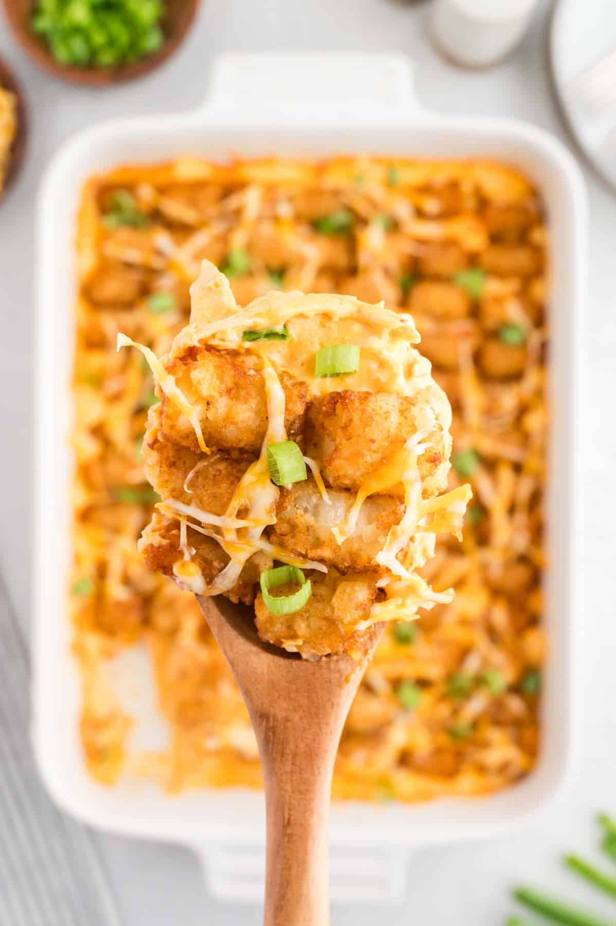 Buffalo Chicken Tater Tot Casserole is an easy family friendly dinner recipe  loaded with rotisserie chicken, cream of chicken soup, cream cheese, ranch dressing, Frank's Red Hot, tater tots, shredded cheese and chopped green onions.