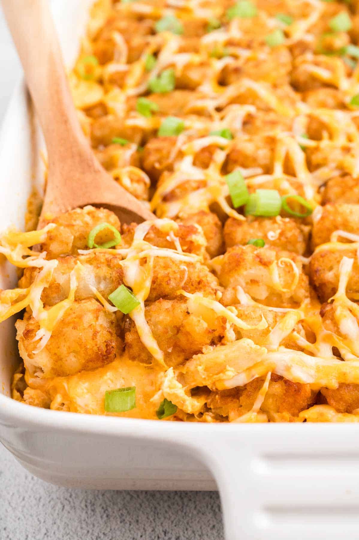 Buffalo Chicken Tater Tot Casserole is an easy family friendly dinner recipe  loaded with rotisserie chicken, cream of chicken soup, cream cheese, ranch dressing, Frank's Red Hot, tater tots, shredded cheese and chopped green onions.