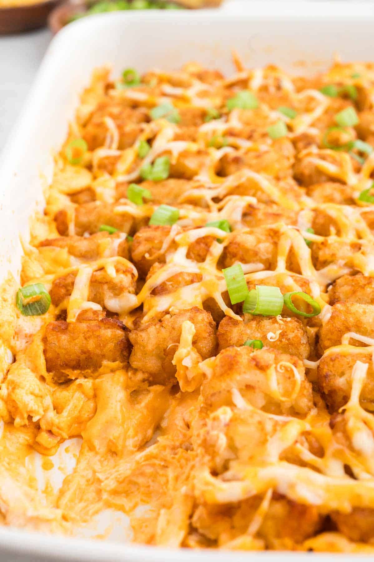 Buffalo Chicken Tater Tot Casserole is an easy family friendly dinner recipe  loaded with rotisserie chicken, cream of chicken soup, cream cheese, ranch dressing, Frank's Red Hot, tater tots, shredded cheese and chopped green onions.