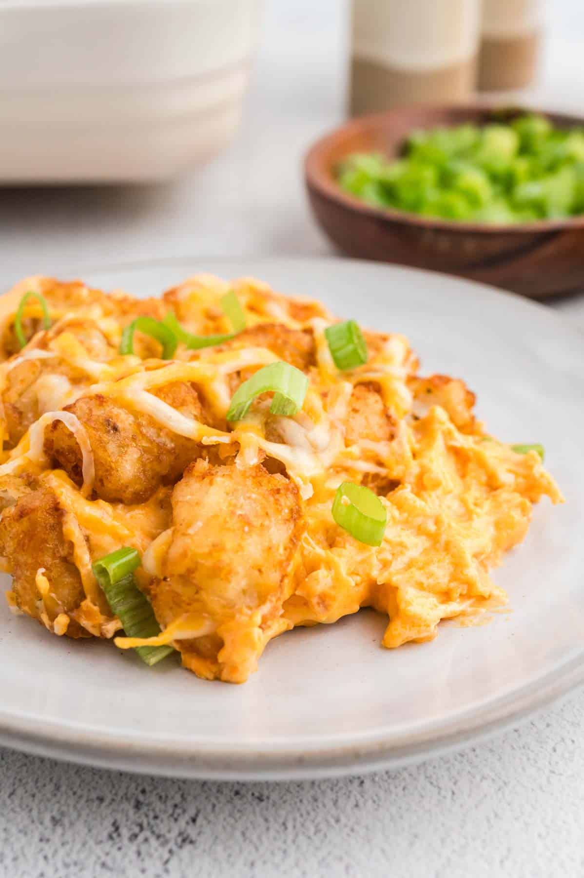 Buffalo Chicken Tater Tot Casserole is an easy family friendly dinner recipe  loaded with rotisserie chicken, cream of chicken soup, cream cheese, ranch dressing, Frank's Red Hot, tater tots, shredded cheese and chopped green onions.