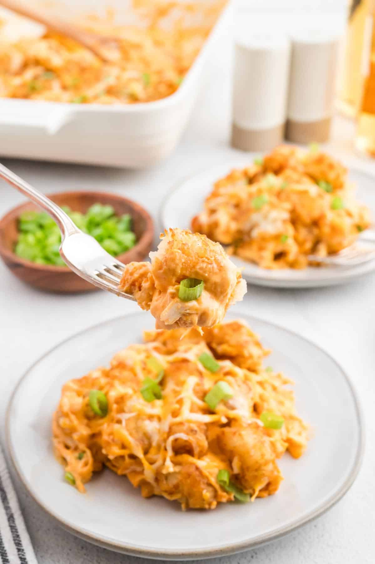 Buffalo Chicken Tater Tot Casserole is an easy family friendly dinner recipe  loaded with rotisserie chicken, cream of chicken soup, cream cheese, ranch dressing, Frank's Red Hot, tater tots, shredded cheese and chopped green onions.
