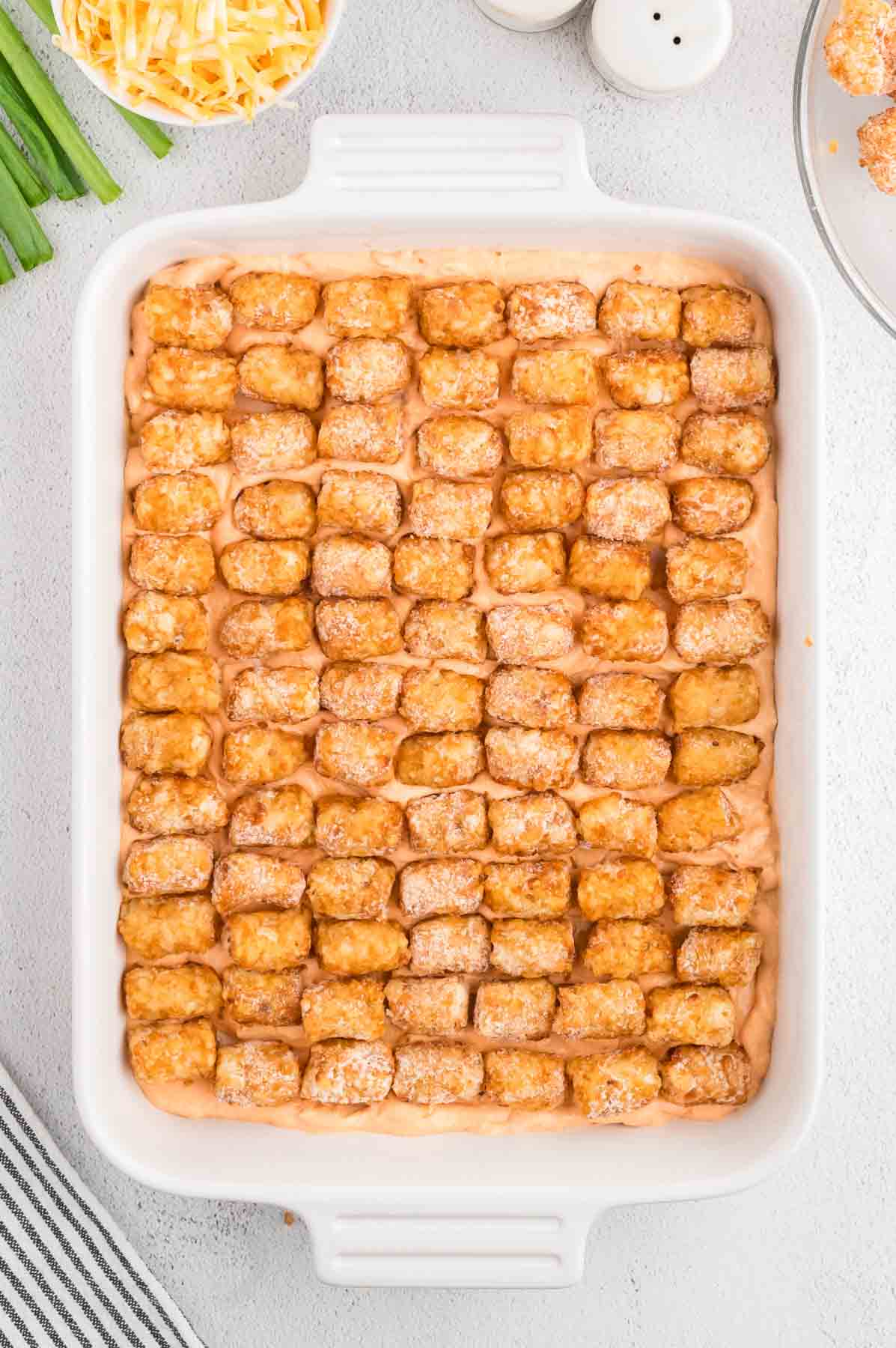 frozen tater tots in a single layer on top of Buffalo chicken mixture in a baking dish