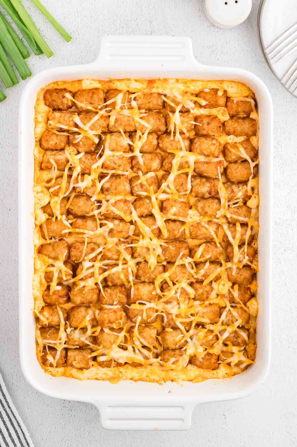 Buffalo Chicken Tater Tot Casserole is an easy family friendly dinner recipe  loaded with rotisserie chicken, cream of chicken soup, cream cheese, ranch dressing, Frank's Red Hot, tater tots, shredded cheese and chopped green onions.