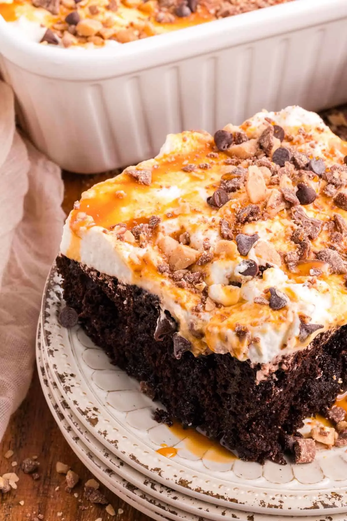 Chocolate Caramel Poke Cake is a decadent chocolate cake soaked with caramel and topped with whipped cream, caramel sauce, chocolate chips and crumbled Heath bars.