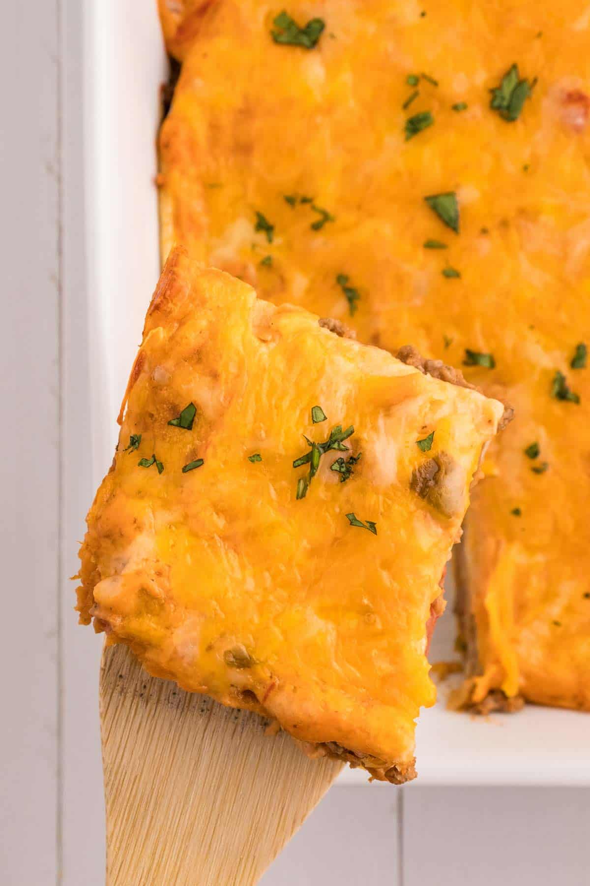 Creamy Burrito Casserole is a hearty dish loaded with flour tortillas, ground beef, refried beans, diced tomatoes, shredded cheese, salsa and sour cream.