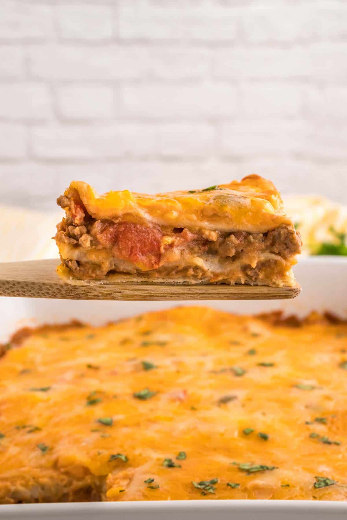 Creamy Burrito Casserole is a hearty dish loaded with flour tortillas, ground beef, refried beans, diced tomatoes, shredded cheese, salsa and sour cream.