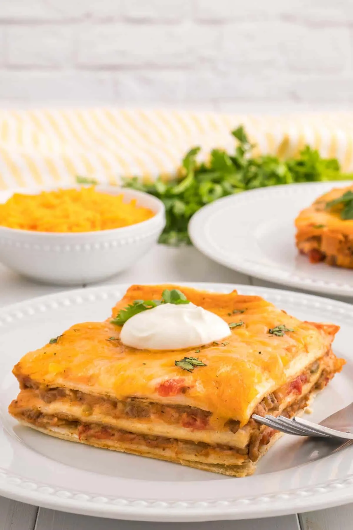 Creamy Burrito Casserole is a hearty dish loaded with flour tortillas, ground beef, refried beans, diced tomatoes, shredded cheese, salsa and sour cream.