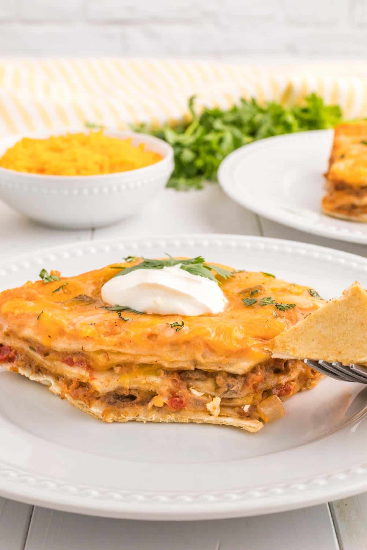 Creamy Burrito Casserole is a hearty dish loaded with flour tortillas, ground beef, refried beans, diced tomatoes, shredded cheese, salsa and sour cream.