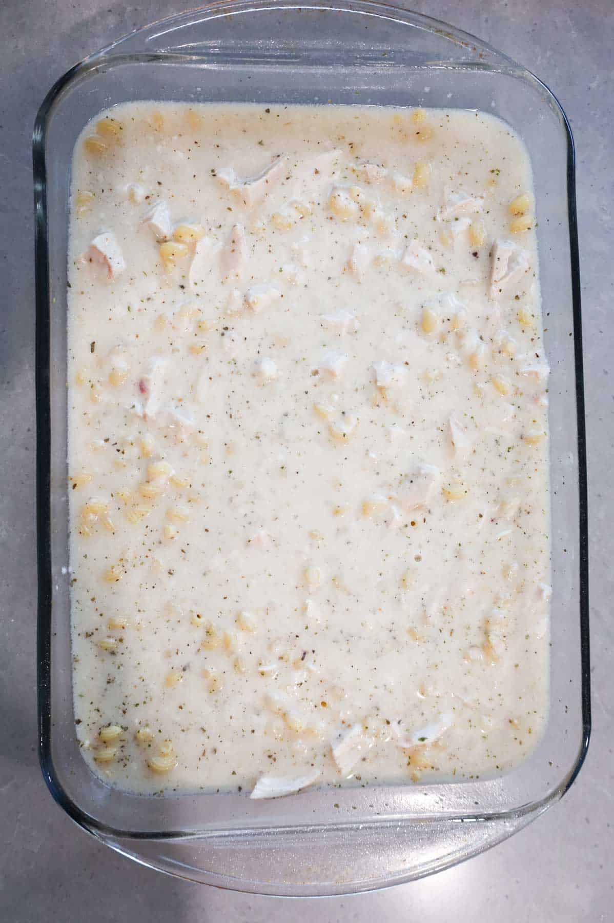 dump and bake chicken alfredo ingredients stirred together in a baking dish